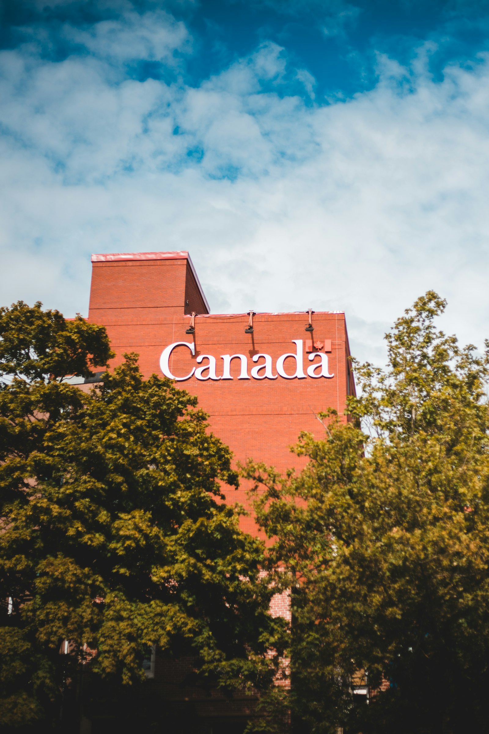 加拿大红砖建筑上的 Canada 字样,夏日绿树环绕