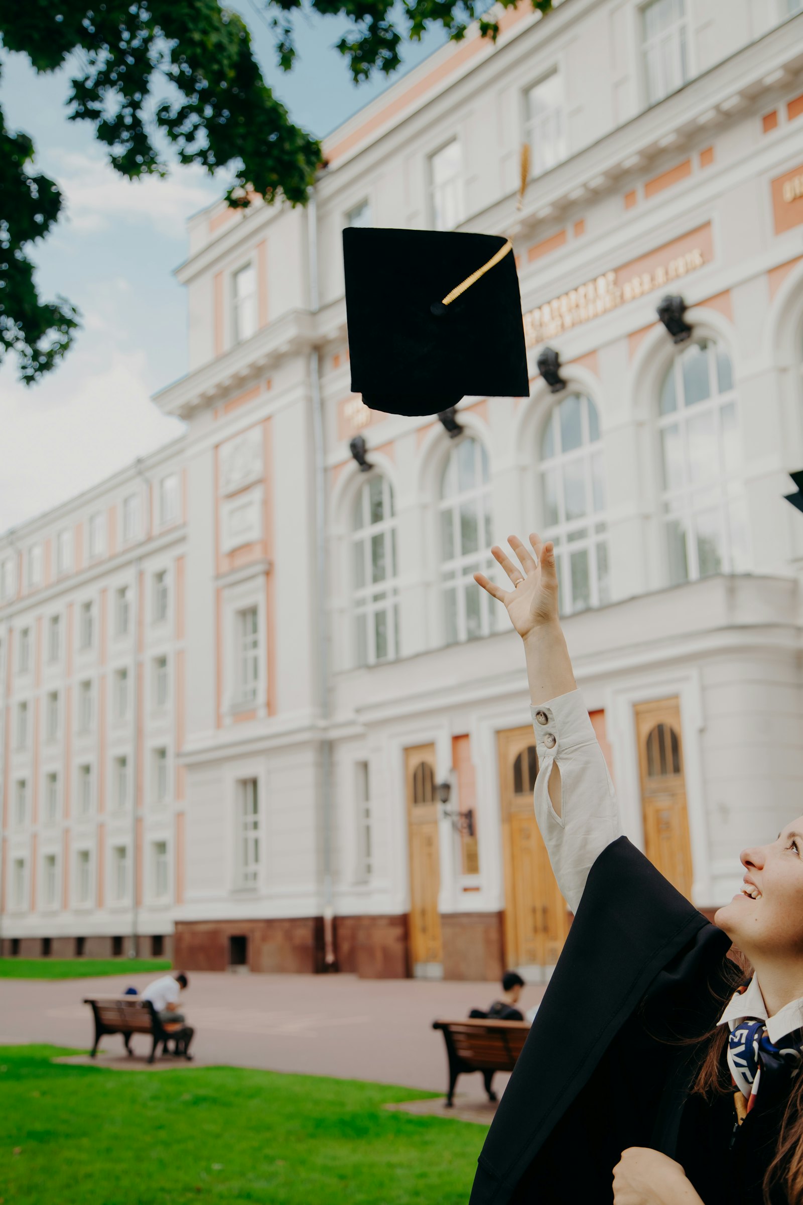 毕业生在大学建筑前抛起学士帽庆祝毕业